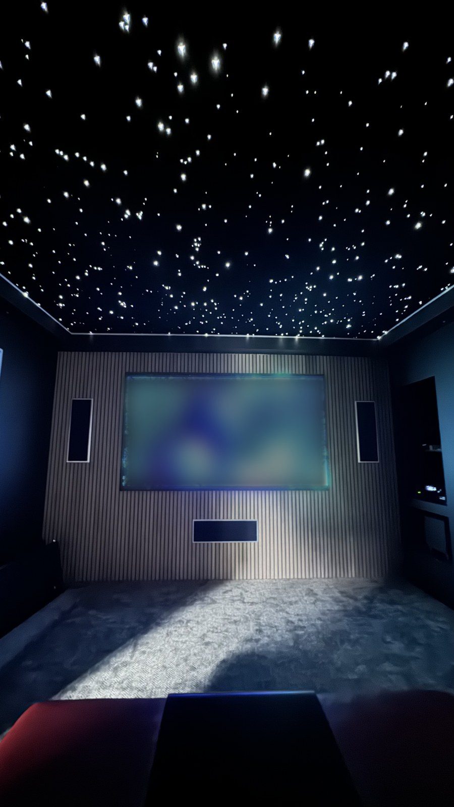 Home cinema with fibre-optic star ceiling, slatted feature wall and screen